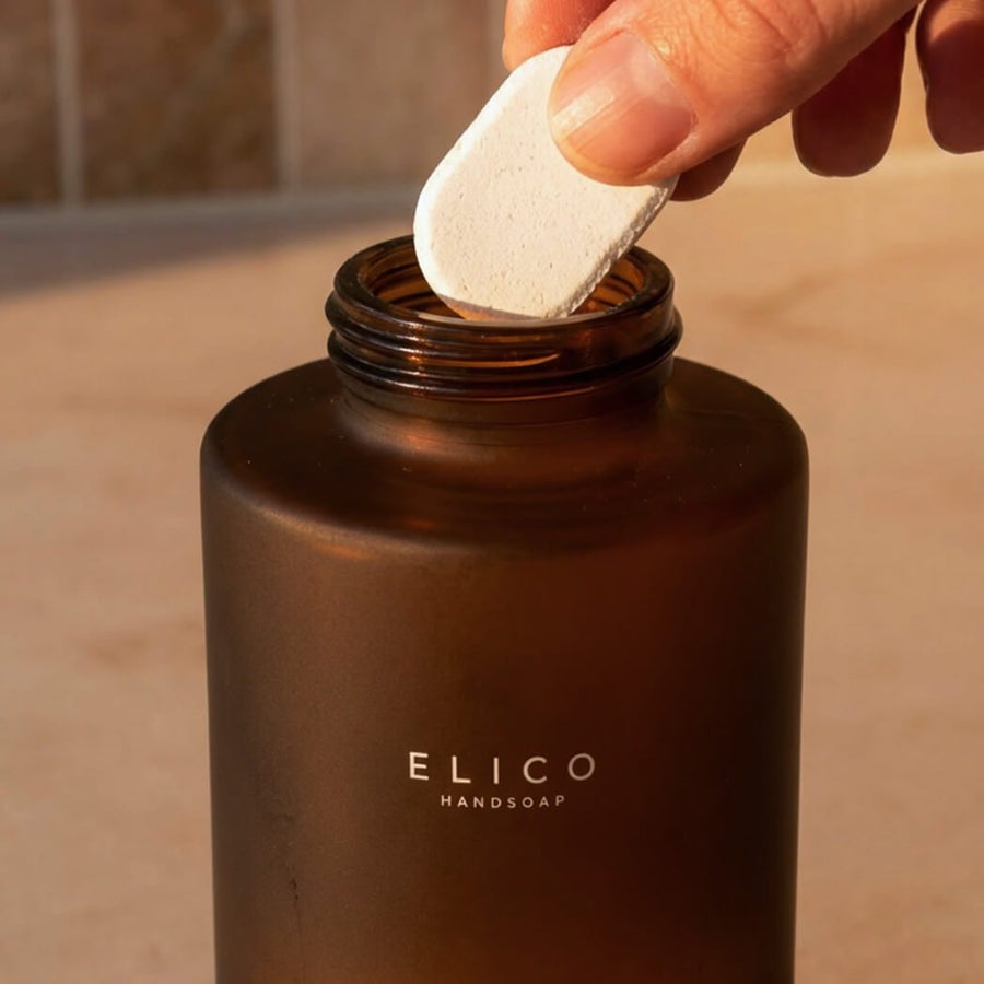 En refill-tablett som släpps ner i en dispenser av bärnstensglas